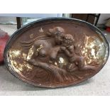 An oval cast iron Victorian wall or fire back plaque depicting classical nude figures. Size approx