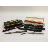 A collection of vintage fountain pens and a lighter.