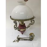 A painted ceramic and brass hanging oil lamp with white glass shade, approx