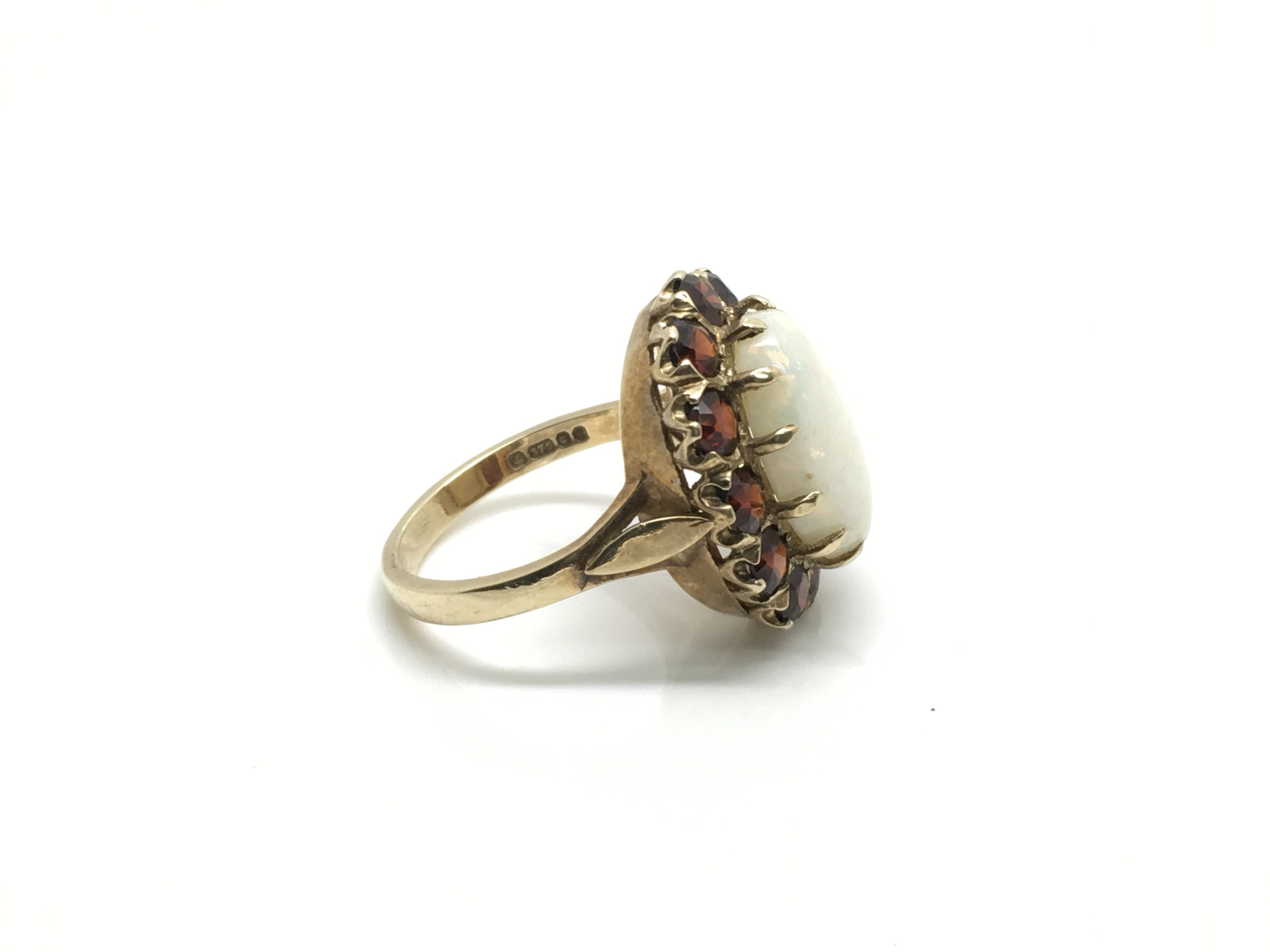 A ladies 9ct gold ring inset with a large central opal surrounded by 12 garnet rubies, ring size - Bild 2 aus 3