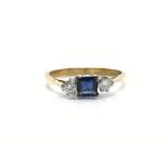 An 18ct gold engagement ring set with a square sapphire flanked by diamonds. Approx size O, total