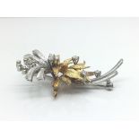 An 18ct yellow and white gold brooch with foliage influence decorated with 13 diamonds. Total weight