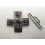 A silver buckle in a cross design with purple ston