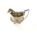 A silver hallmarked cream jug with foliage decorat