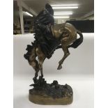 A bronzed Frederic Remington figure of a cowboy on