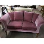 A Pink draylon upholstered two seater sofa with a