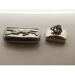 A silver snuff box with a dog design and one with