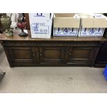 A low oak sideboard with carved frieze above three