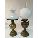 Two brass oil lamps with white glass shades.