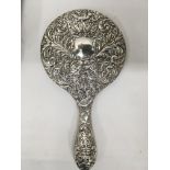 A silver backed hand mirror with a classical desig