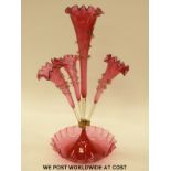 A cranberry glass epergne, the four flutes each with applied clear glass decoration, 52cm tall.