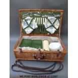 A retro picnic hamper with china plates, metal cutlery, thermos, leather straps etc.