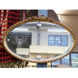 An oval mirror with bevelled glass,