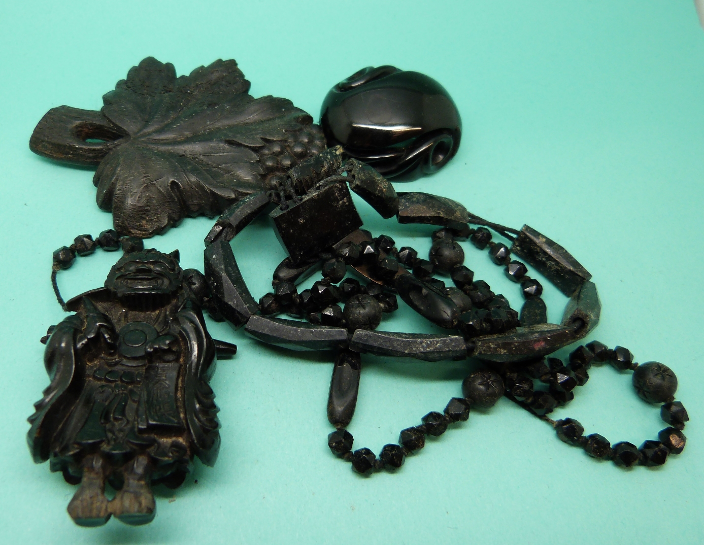 A jet netsuke in the form of a Japanese creature and three other pieces of Victorian jet