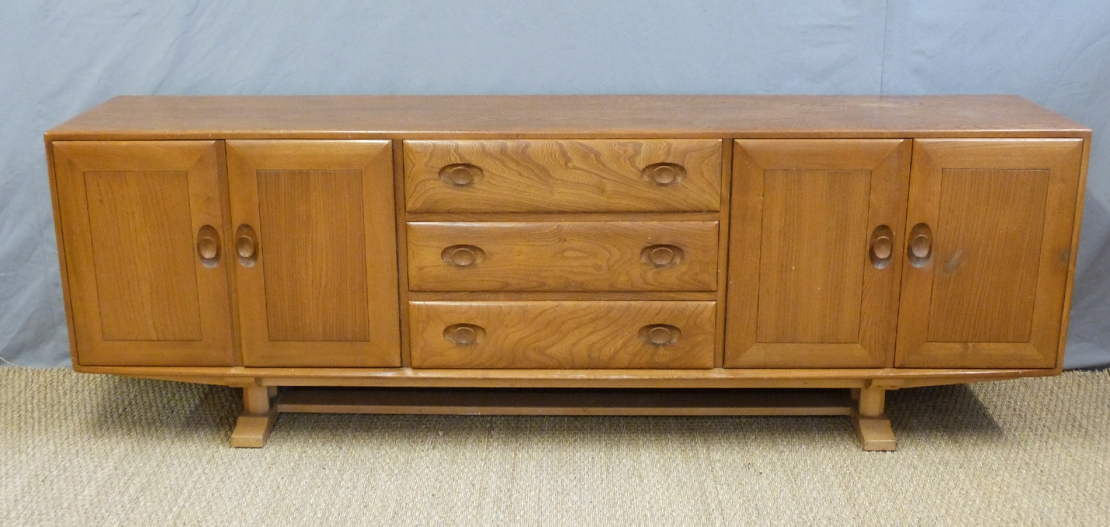 A retro Ercol light elm long sideboard with an arrangement of two double cupboards each end and