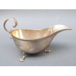 An Edward VII hallmarked silver sauce boat raised on three feet with scroll handle, Chester 1909,