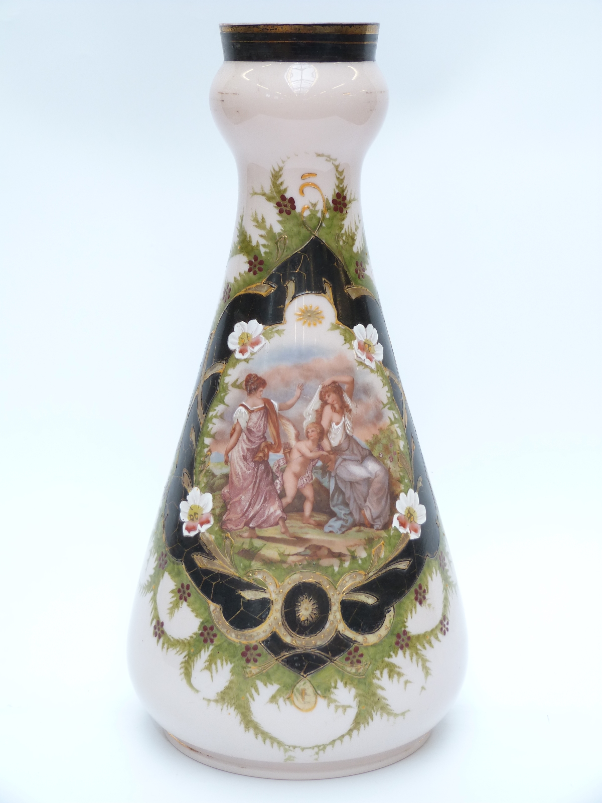 A large glass vase decorated with a scene of ladies and a cherub in a landscape setting surrounded