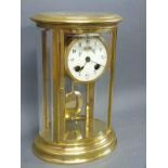 A brass cased mantel clock with four bevelled and curved glass panels,