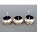 A set of three George V hallmarked silver open salts with blue glass liners, Sheffield 1918,
