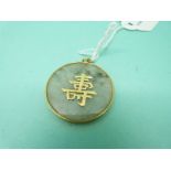A Chinese yellow metal pendant set with a jadeite section and Chinese characters to the centre