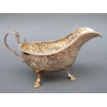 A Victorian hallmarked silver sauce or gravy boat with scroll handle raised on three feet,