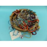 A round wooden bowl containing costume jewellery, silver bangle, agate necklace,