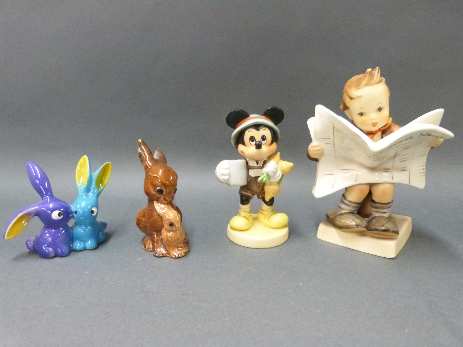 Four Goebel Hummel figures including boy reading newspaper, Mickey Mouse and unusual rabbits, - Image 2 of 3