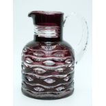 An amethyst flash overlaid glass water jug with cut decoration and applied handle,