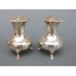 A pair of George V hallmarked silver peppers raised on three feet, Sheffield 1934,