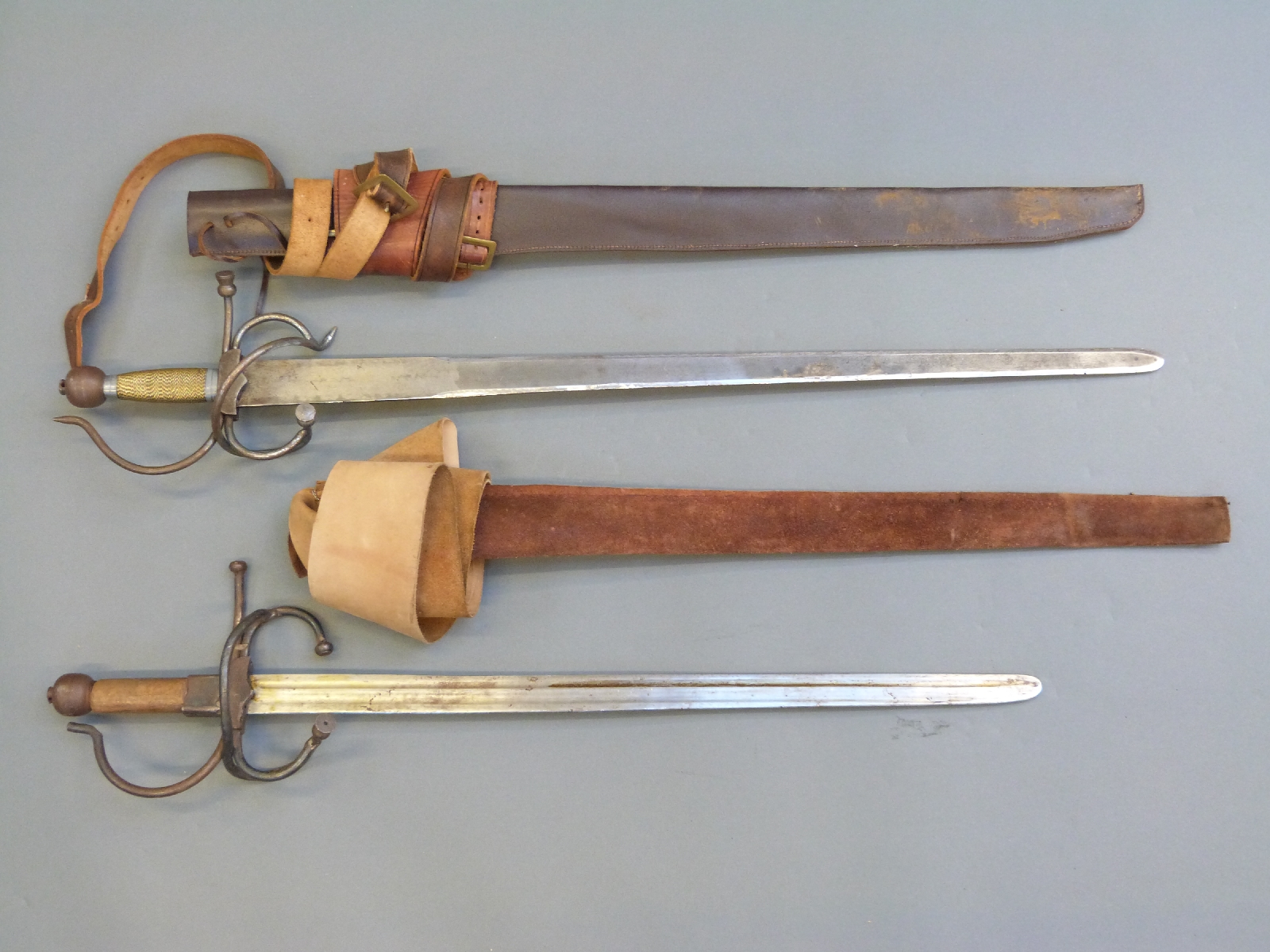 A pair of replica English Civil War swords with leather scabbards and belts,