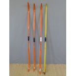 Four various fibreglass archery bows three in orange and one yellow.