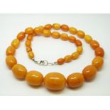 An amber necklace of 35 graduated ovoid egg yolk coloured beads, the largest approximately 27x22mm,