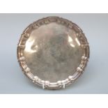 A George V hallmarked silver salver with shaped edge, raised on three feet,