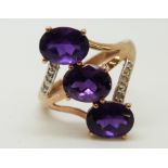 A 9ct gold ring set with three oval amethysts and diamonds (size O)