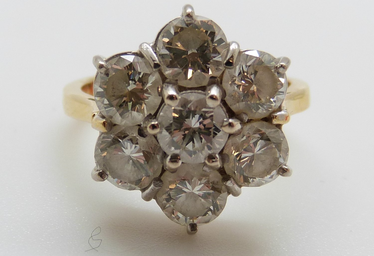 An 18ct gold ring set with seven round brilliant cut diamonds in a cluster,