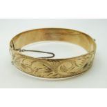 A 9ct gold bangle with engraved foliate design, 55.