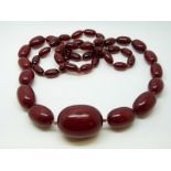 A cherry amber necklace of 49 graduated ovoid beads, the largest approximately 33x24mm, 67g,