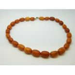 An amber necklace of 26 graduated ovoid egg yolk coloured beads, each approximately 17x12mm, 31g,
