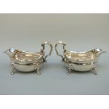 A pair of large Georgian hallmarked silver sauce boats with shaped edges and scrolling handle,
