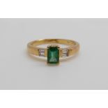 An 18ct gold ring set with an emerald cut emerald of approximately 0.