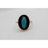 A yellow metal ring set with black onyx with a turquoise to the centre (size M)