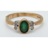 A 9ct gold ring set with an oval emerald and four diamonds (size N)