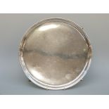 A George V hallmarked silver circular salver raised on hoofed feet,