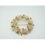 A 14k gold brooch set with cornflower blue sapphires in a foliate wreath design, 4.