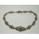 An early 20thC white metal necklace of floral design set with foiled paste
