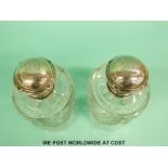A pair of Fabergé silver topped cut glass scent bottles with ribbon decoration,