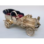 An Indian white metal novelty model veteran car with turning wheels,