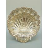 An Edward VII hallmarked silver pierced shell shaped bonbon dish raised on three ball feet,