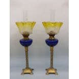 A pair of oil lamps with blue glass reservoirs,