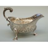 A Georgian hallmarked silver sauce boat with repousse decoration and scroll handle,
